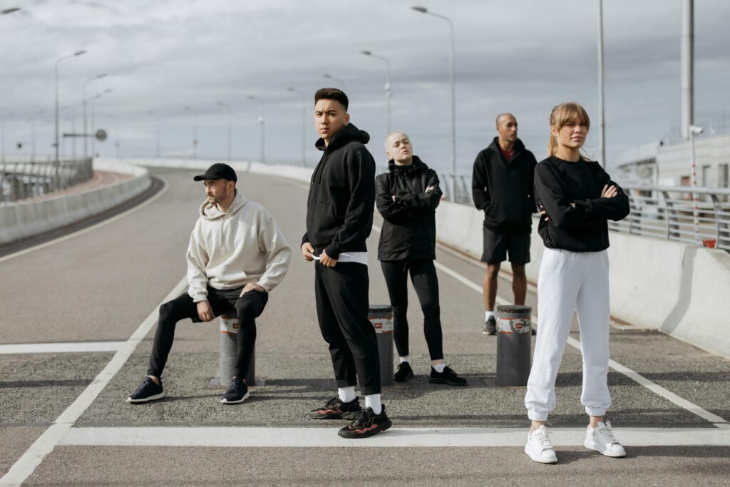 A diverse group of stylish adults posing in sportswear on an urban street.